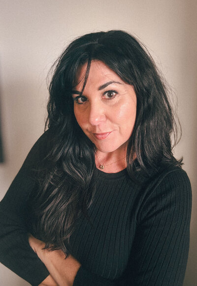 Lisa Bennett, founder of ReDesign, standing by a window in an elegant black outfit, exuding confidence and warmth.