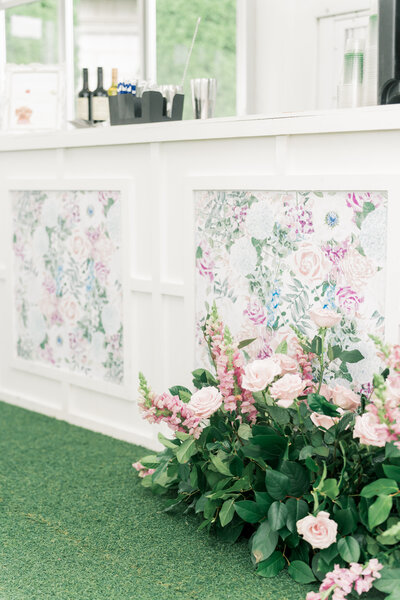 Custom wedding bar with floral panels and fresh pink flowers, part of wedding day stationery.