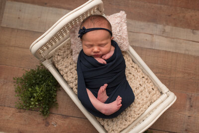 Baby girl wrapped in navy wrap in white bed