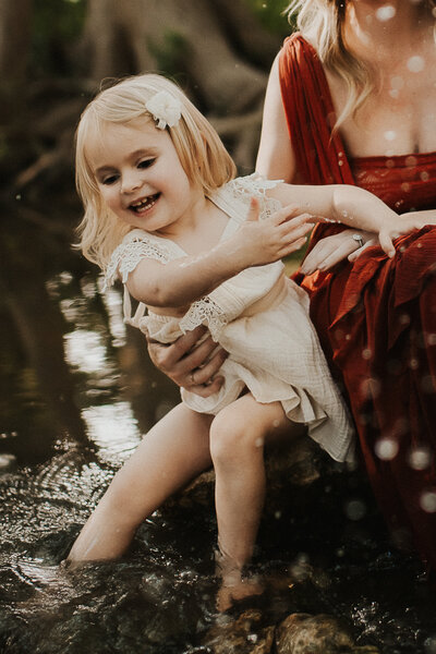 Little girl splashing water in a creek