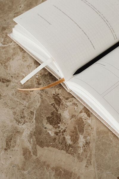 Minimalist open notebook with ribbon bookmarks on a marble surface, ready for planning and organization