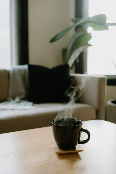 Mug of coffee next to a cozy chair.