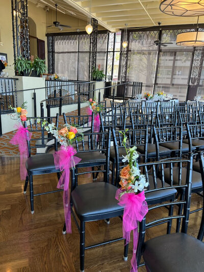 Rows of black chairs adorned with pink ribbons and floral arrangements