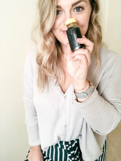 Mollie Mason holding up a wellness shot in front of her face