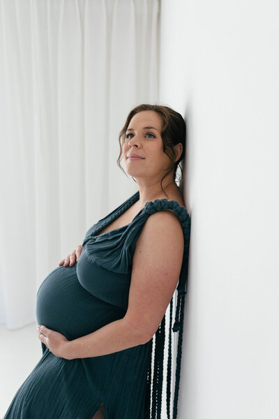 Pregnant women leans against the wall during her photoshoot
