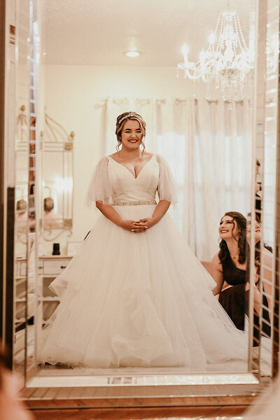 Bride smiles into the mirror after getting ready for her wedding at this Orlando wedding venue.