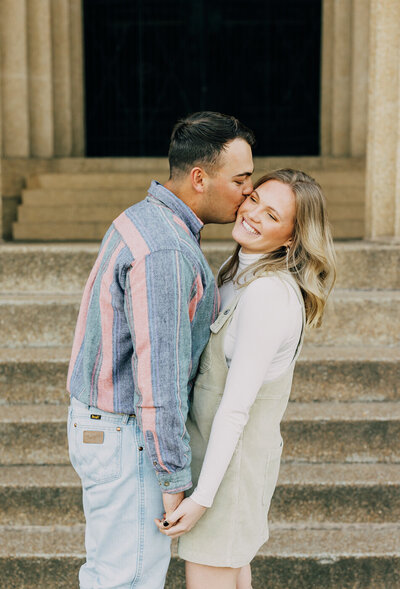 Couple embracing while sitting on a wall next to a pond