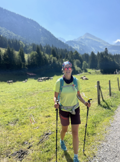 Moderatorin Hanna Zöller beim Wandern mit Stöcken auf einer Bergwiese, Natur und Outdoor als Ausgleich zur Eventmoderation