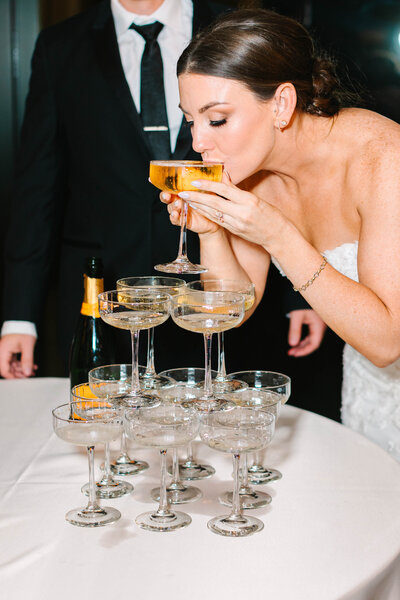 Flash photo of bride sipping from a champagne tower