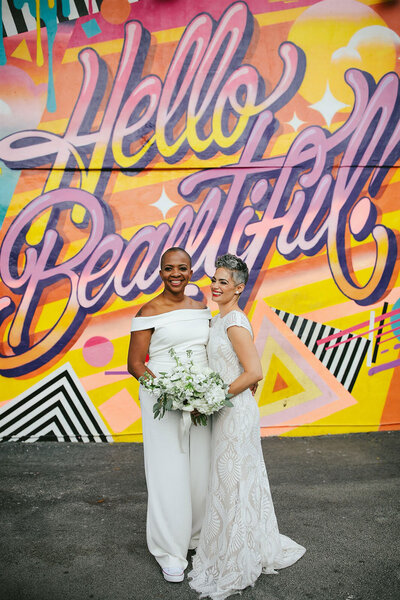 Two Brides in front of a Colorful Mural in Wynwood at their Miami Destination Elopement