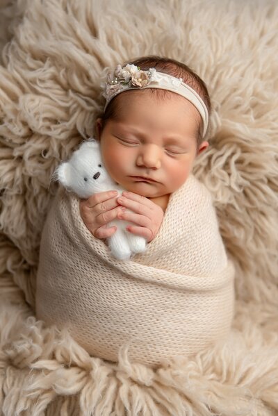 Newborn picture in green swaddle on a newborn bed in brown background in Wellington, FL.