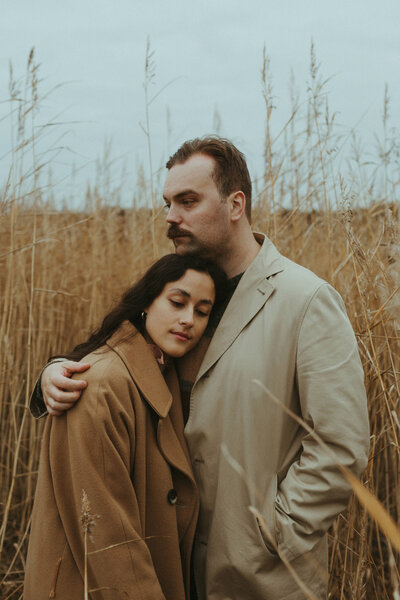 Couple standing in the sea grass hugging at fall in Lauttasaari in Helsinki