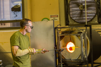 Man inserting glass into furnace for hand blown glass