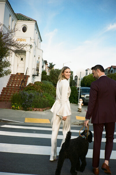 A bride and groom cross the street with their dog in San Francisco after their elopement