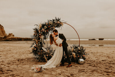 Bride and groom kissing on their beach wedding