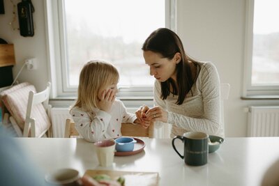 En mamma tittar på sin dotters hand under en familjefotografering i Göteborg
