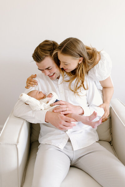 Couple holding and smiling at newborn baby during photos session with Indianapolis newborn and family photographer Capturing Simplicity Photography