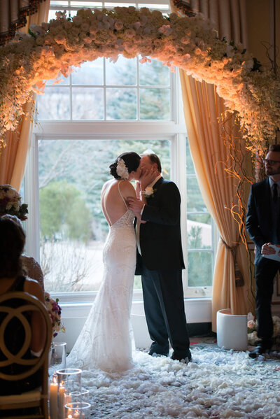 Bride and groom's first kiss at the close of their ceremony inside The Broadmoor at the Lake Terrace Dining Room