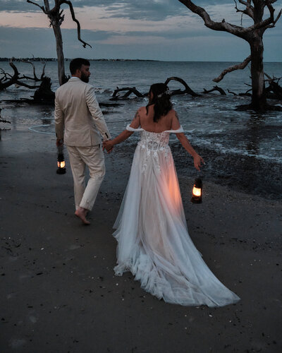 Wedding couple walking on a beach at blue hour with lanterns