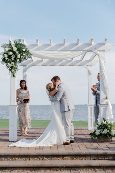 A couple shares their first kiss at their Rehoboth Beach Country Club wedding. Photographed by Christopher Ginn Studios.