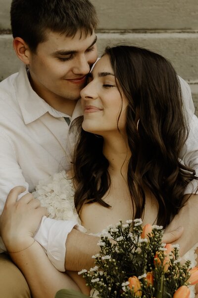 Newlyweds sit together, snuggling their faces close following their elopement ceremony.