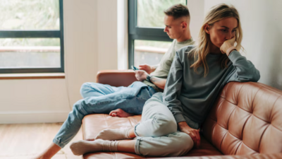 Couple sitting on a couch, facing away from each other and disengaged in the roommate phase – representing relationship support and couples counselling with Freedom Couple Counselling in Melbourne.