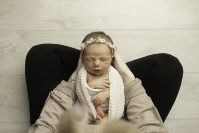 A loving moment captured of a mother gently holding her newborn, wrapped in a soft, cozy blanket. The tender embrace highlights the deep connection between them, with the baby's tiny features peacefully nestled against the mother’s chest, radiating warmth and comfort