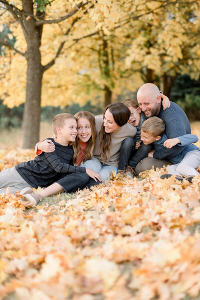 family snuggling in the fall leaves