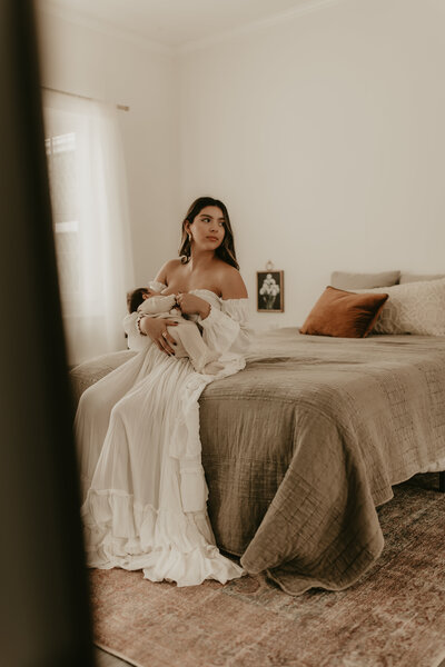 New mother cradling newborn baby while sitting in nursery rocking chair, captured during lifestyle newborn session – Morristown, NJ