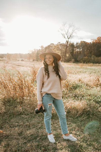 Charlotte family photographer Tonya Cassibry smiling while photographing a family session in a sunlit field.