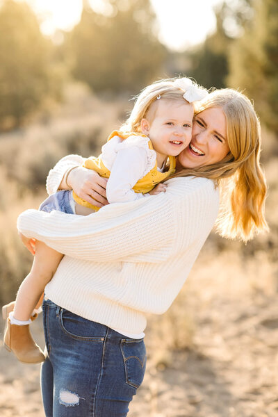 blonde mother embracing little girl in yellow dress