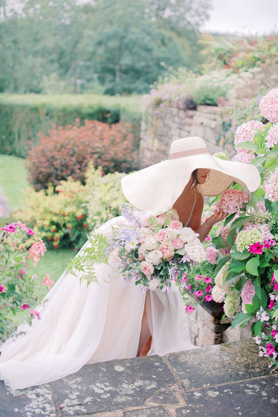 Tulle wedding dress and oversized sun hat bridal fashion as a bride explores the manicured gardens of her European wedding venue