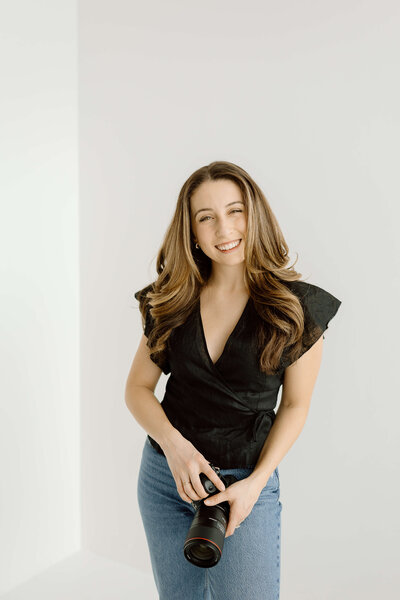 Clarissa, the owner of Golden Hour Photo Co, holding up her camera at Mint Room studios in Toronto.