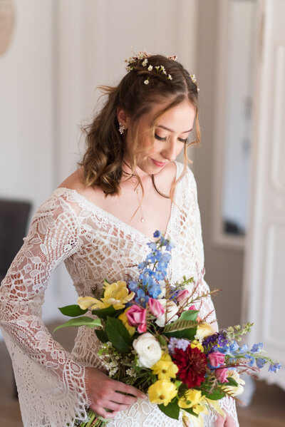 Bride smiles down at her bouquet inside the venue The Barn at Raccoon Creek in Littleton, Colorado