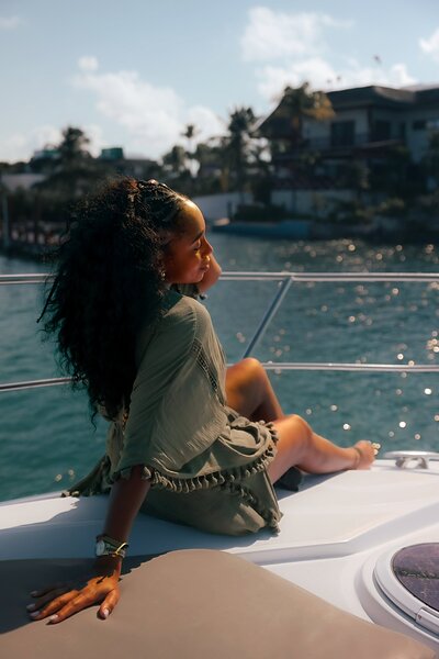 Woman sits on a boat in an olive-colored caftan