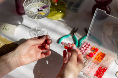 Hier worden kralen geregen aan tafel tijdens een workshop Beads & Sips.