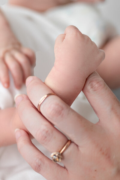 A newborn baby holding his mother's finger