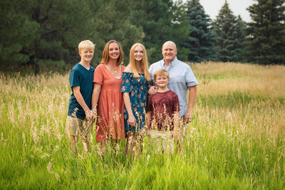 family of five standing together in a green grassy field