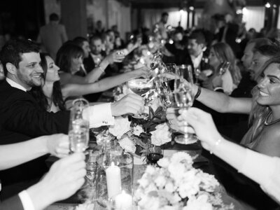 Celebratory toast at a family style table and an outdoor venue with string lights