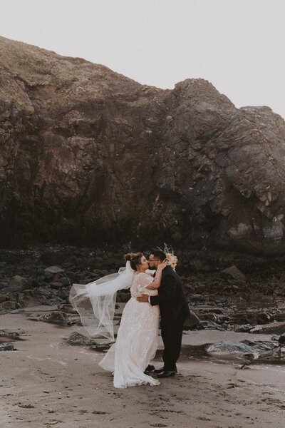 Couple in wedding attire at an Oregon Coast beach for their elopement