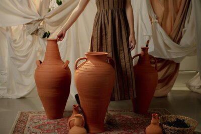 Woman in green dress stands behind large terracotta pots