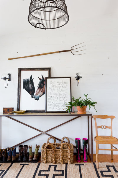 Iron entry table with boot storage, white shiplap wall with pitchfork, and basket light fixture
