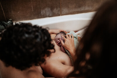 El Paso Mom and Dad in bathtub holding their new baby after birth.