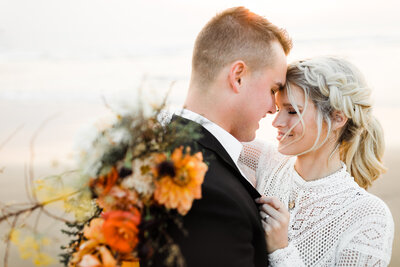 A bride and groom on the beach at sunset,