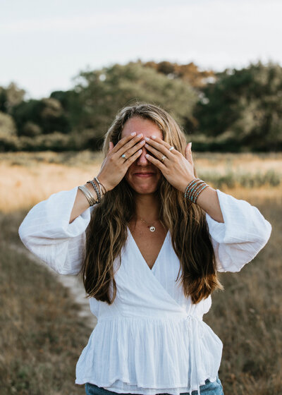 woman smiling with hands covering her face
