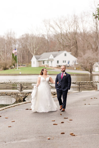Bride smiles up at groom while walking outside away from bride during their Perona Farms wedding in Sparta, NJ