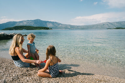 woman smiling on a beach with two kids