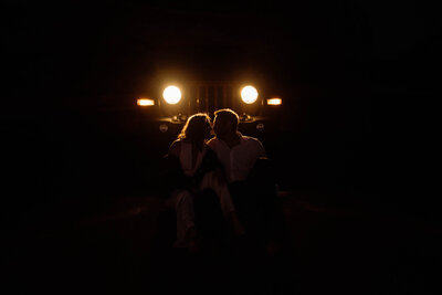 bride and groom sitting in front of the car