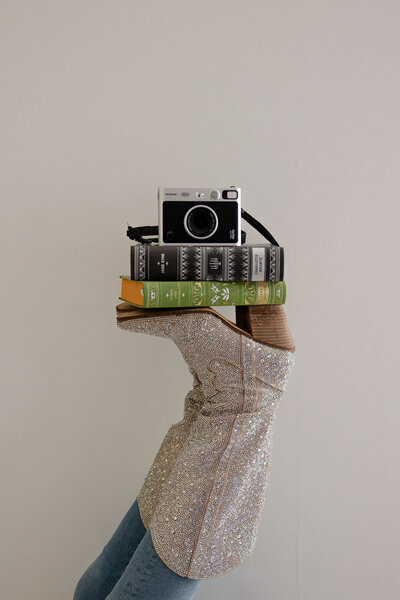 bedazzled boot holding up books and camera