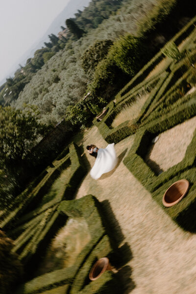 Aerial view of a newlywed couple dancing in an intricate garden 